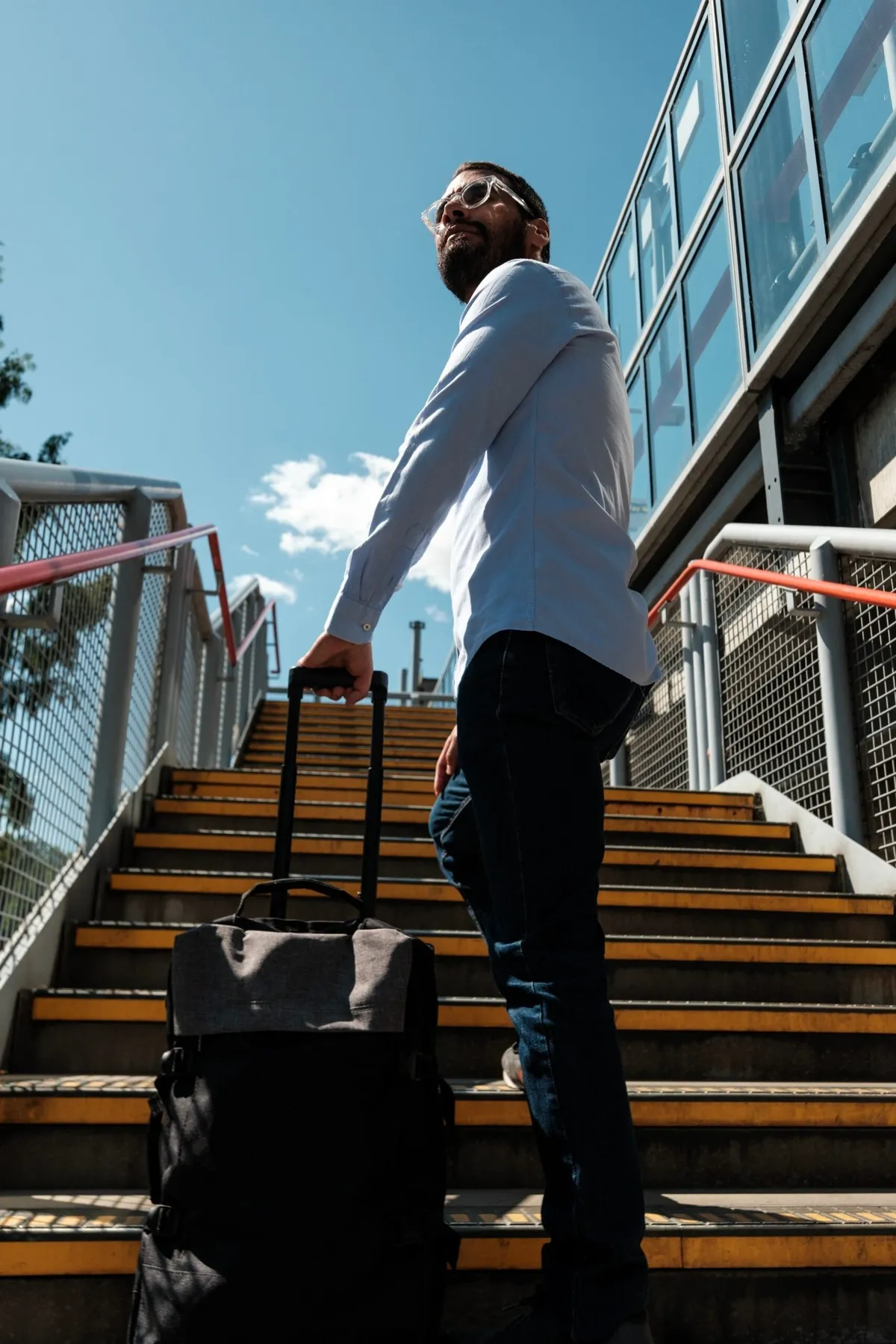 Reisender mit Rollkoffer auf einer Treppe
