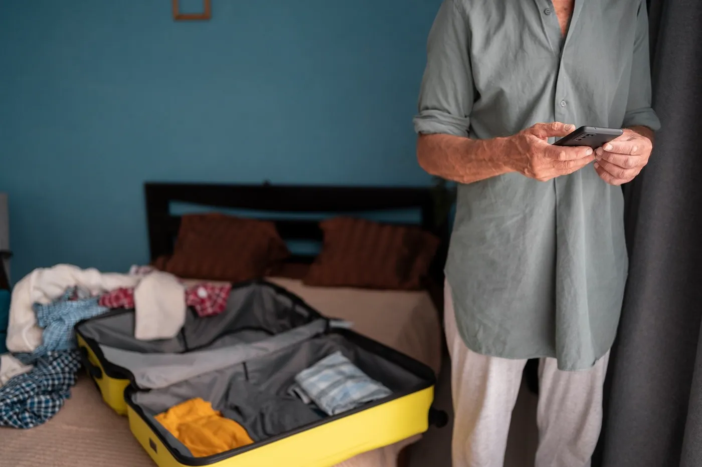 Mann packt den Koffer und prüft die Liste auf dem Smartphone
